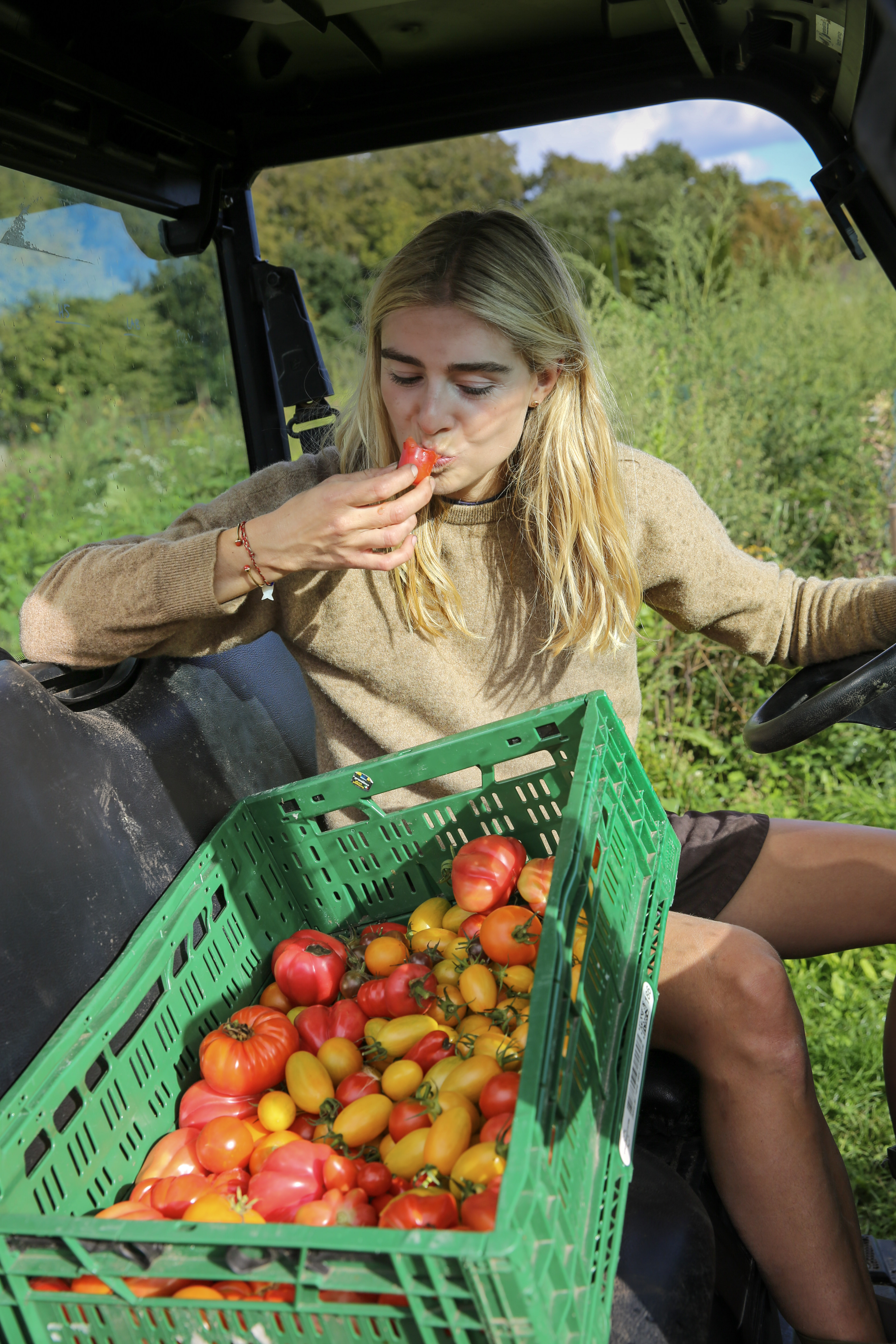 Mathilde eating a tomato in a farm vehicle